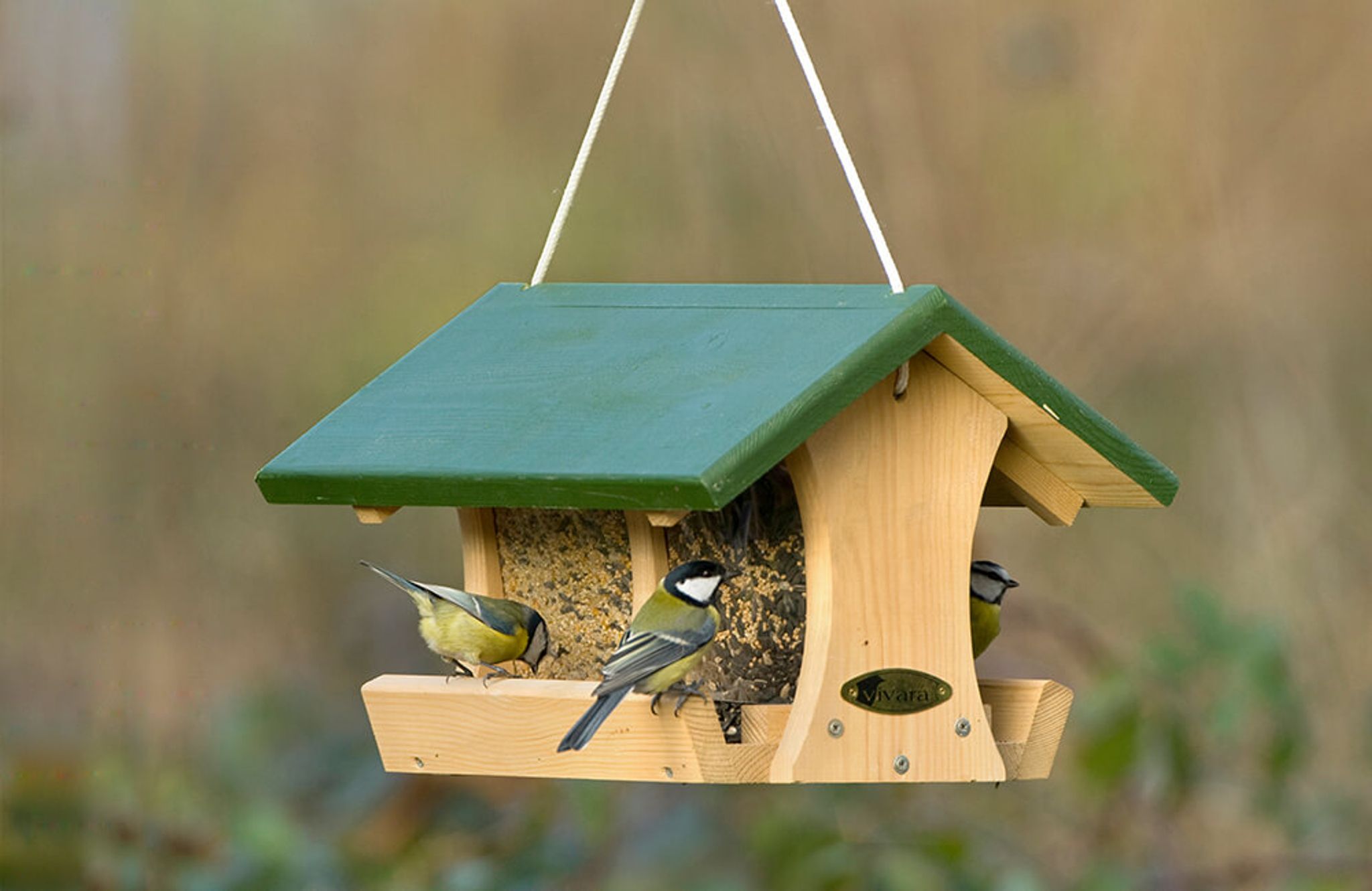 Ein klassisches Vogelfutterhaus aus Holz, worin Saatmischungen verfüttert werden.